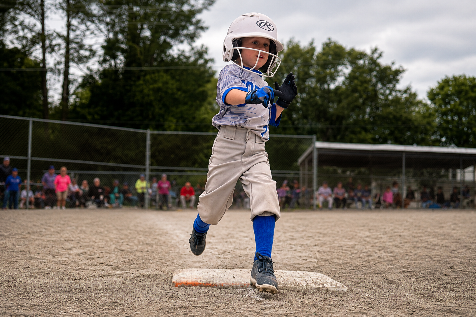 Youth baseball player running across a base